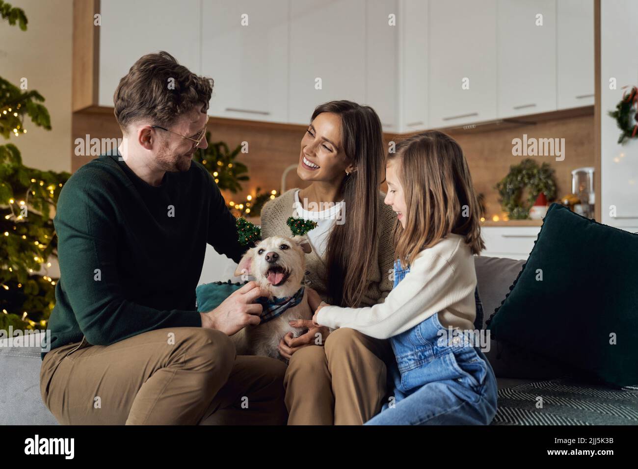 Famiglia sorridente con il cane che si gode il tempo di Natale insieme a casa Foto Stock