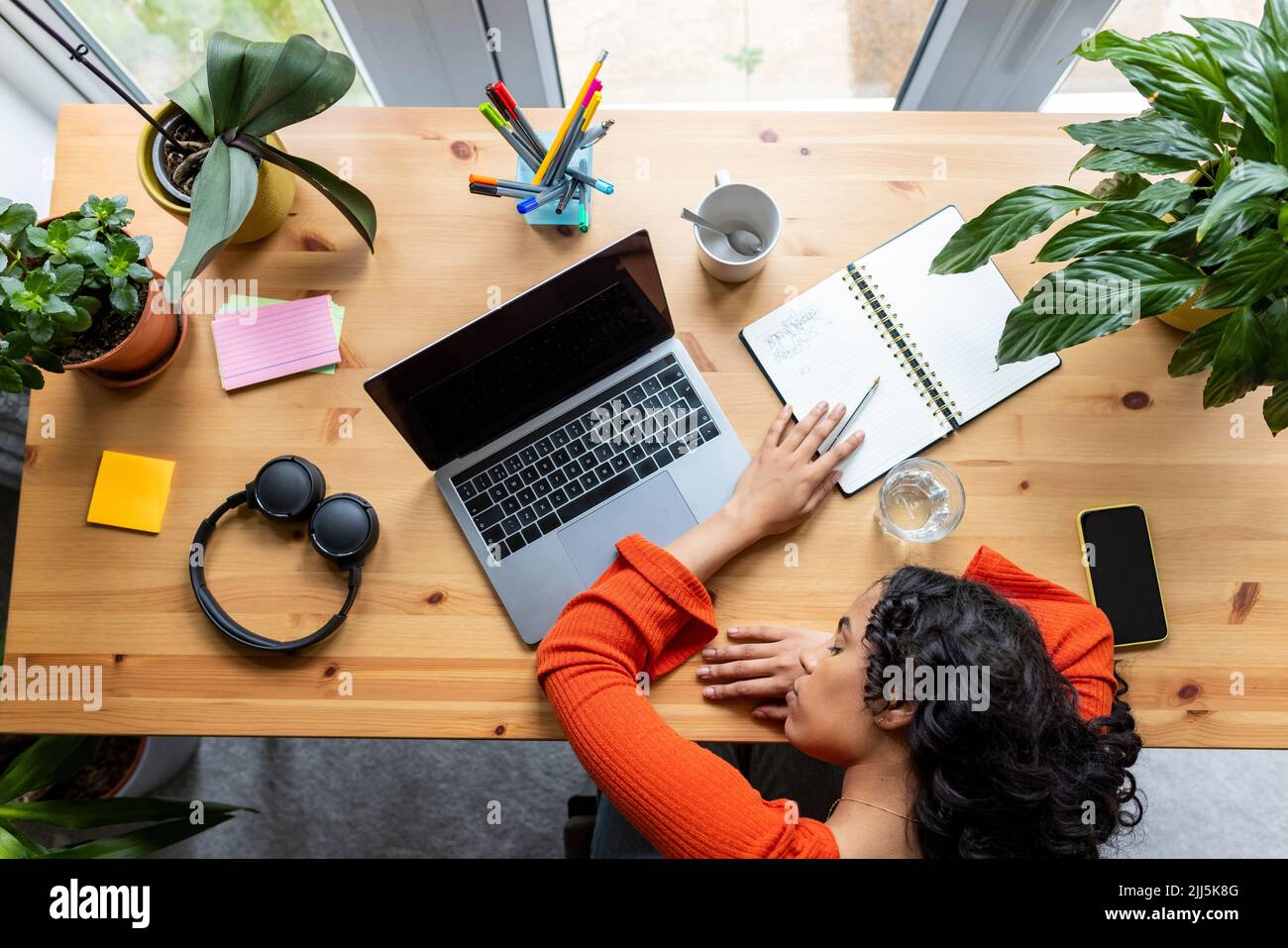 Freelance che riposa sulla scrivania con computer portatile e cuffie in ufficio a casa Foto Stock