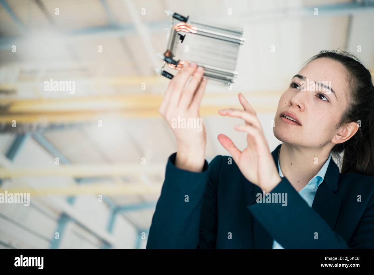 Donna d'affari che analizza parte macchina in fabbrica Foto Stock
