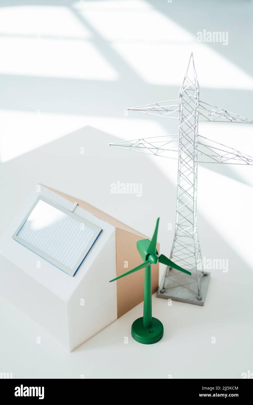 Modello di turbina eolica, casa modello e pilone elettrico sulla scrivania in ufficio Foto Stock Modello di turbina eolica, casa modello e pilone elettrico sulla scrivania in ufficio Foto Stock