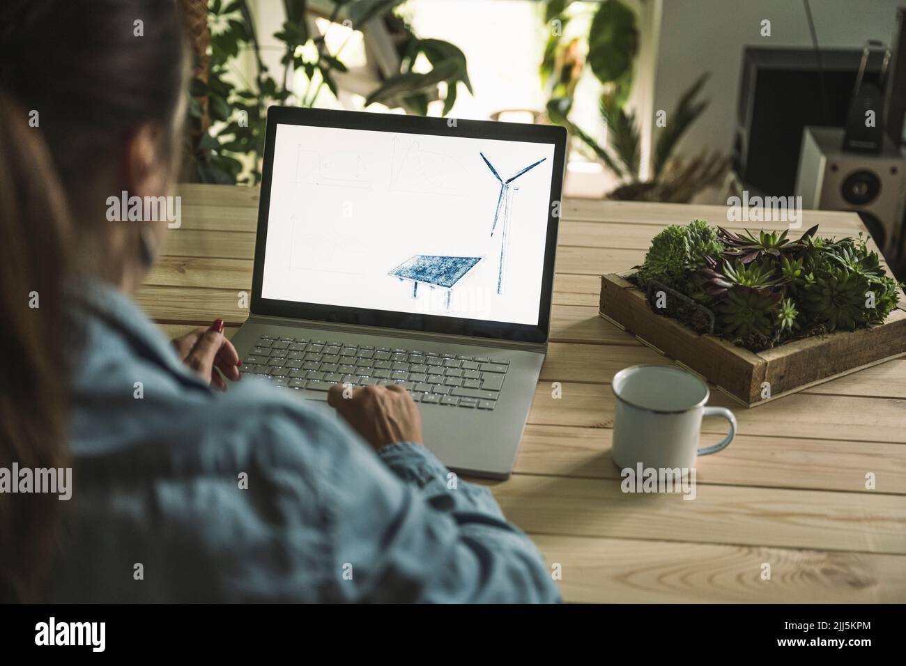 Freelance con schizzo di pannello solare e turbina eolica sullo schermo del computer portatile in ufficio Foto Stock Freelance con schizzo di pannello solare e turbina eolica sullo schermo del computer portatile in ufficio Foto Stock