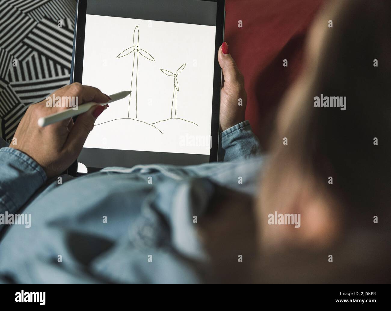 Freelance che crea uno schizzo di turbine eoliche su un tablet grafico a casa Foto Stock Freelance che crea uno schizzo di turbine eoliche su un tablet grafico a casa Foto Stock