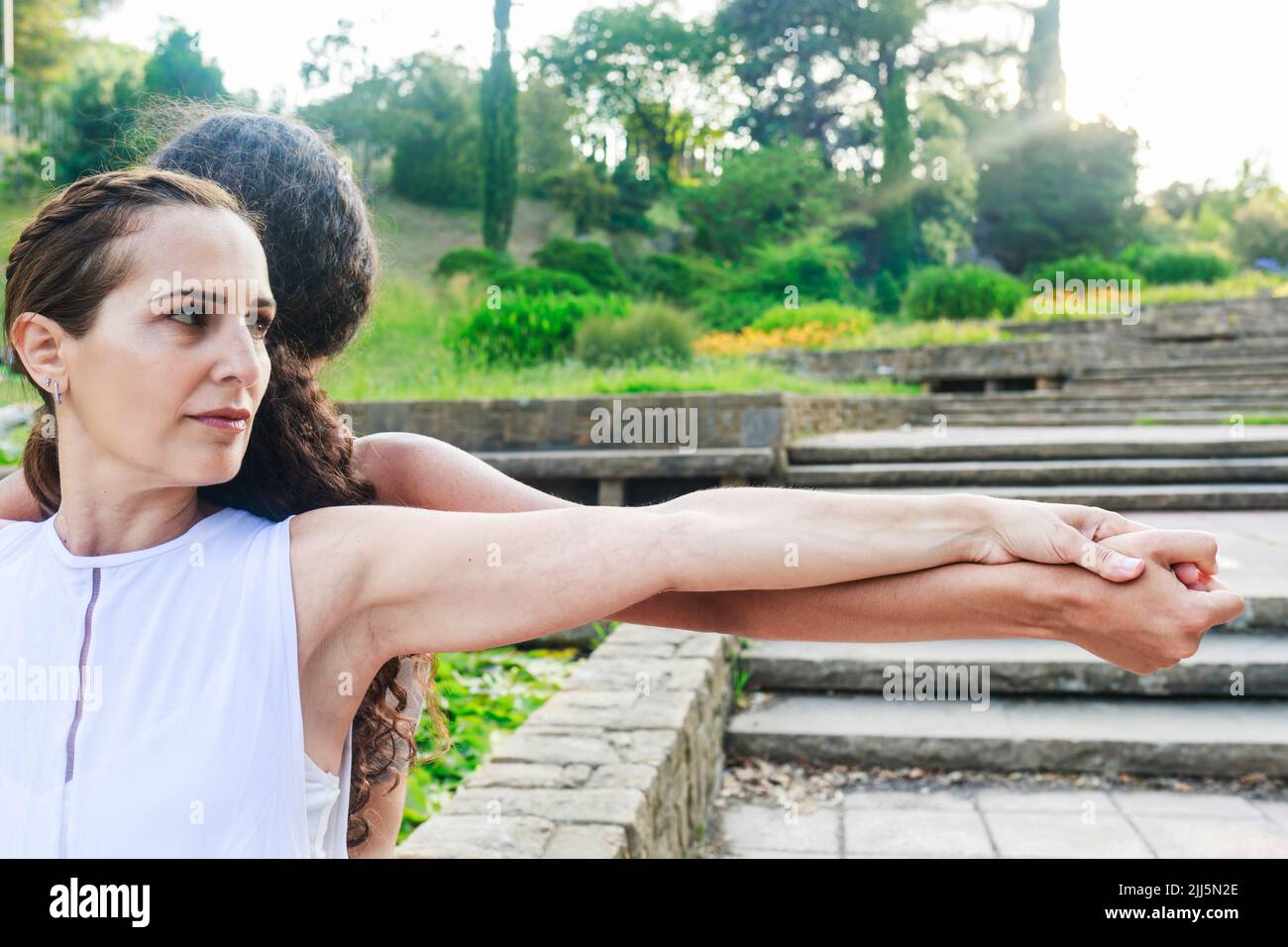 Donna e ragazza che si allenano di yoga con le braccia tese al parco Foto Stock
