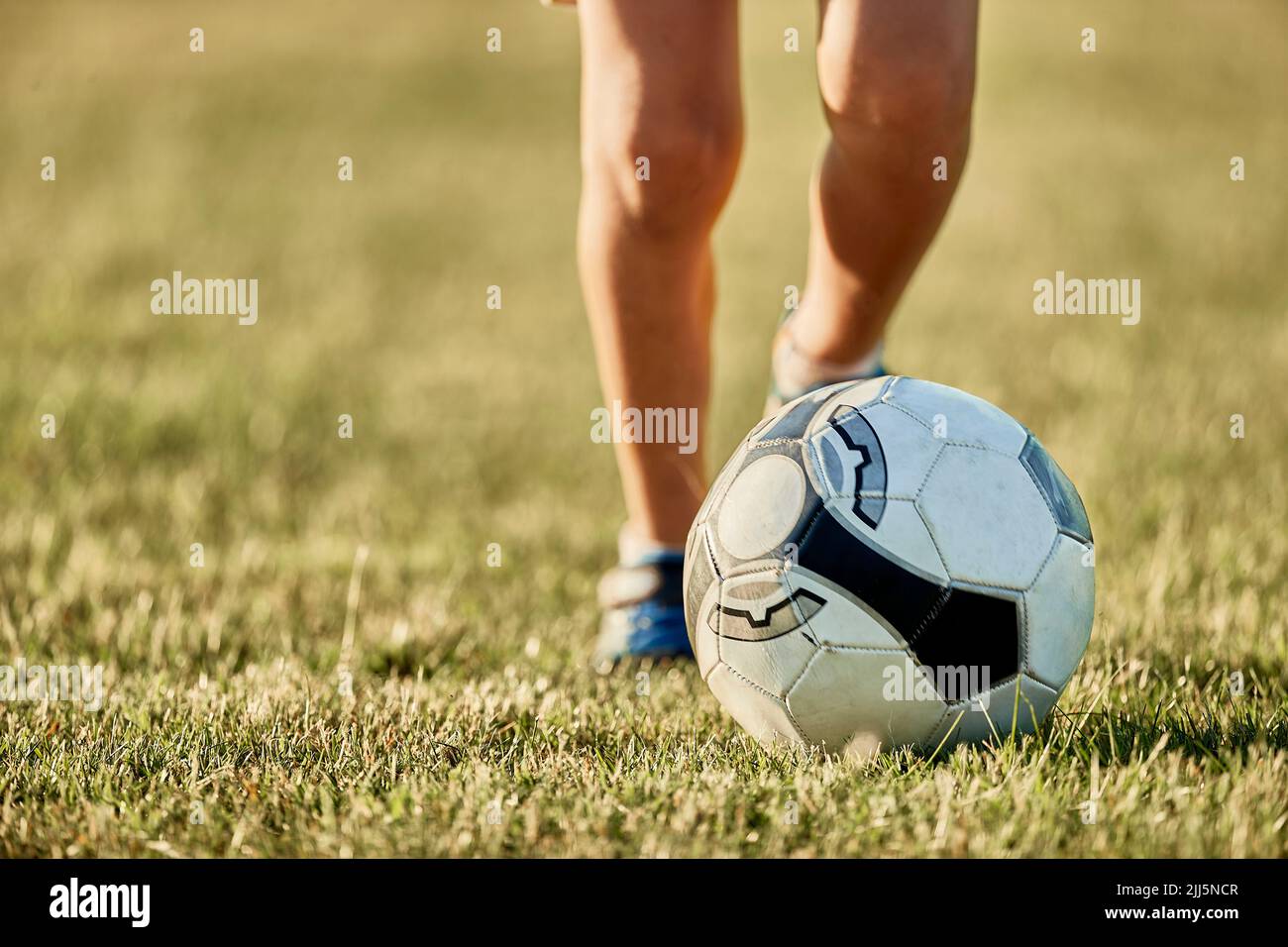 Gambe di ragazzo di fronte alla palla di calcio in campo sportivo Foto Stock