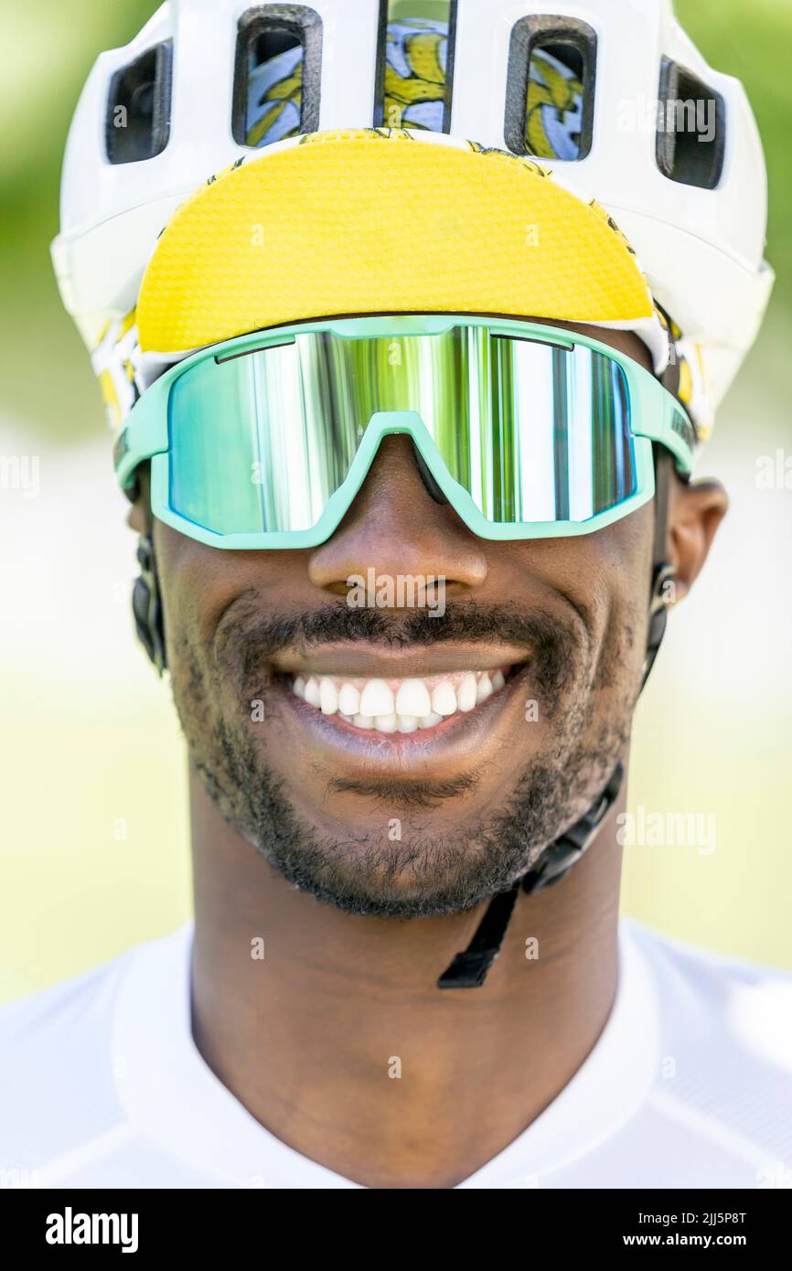Uomo felice che indossa casco da ciclismo e occhiali da sole Foto Stock