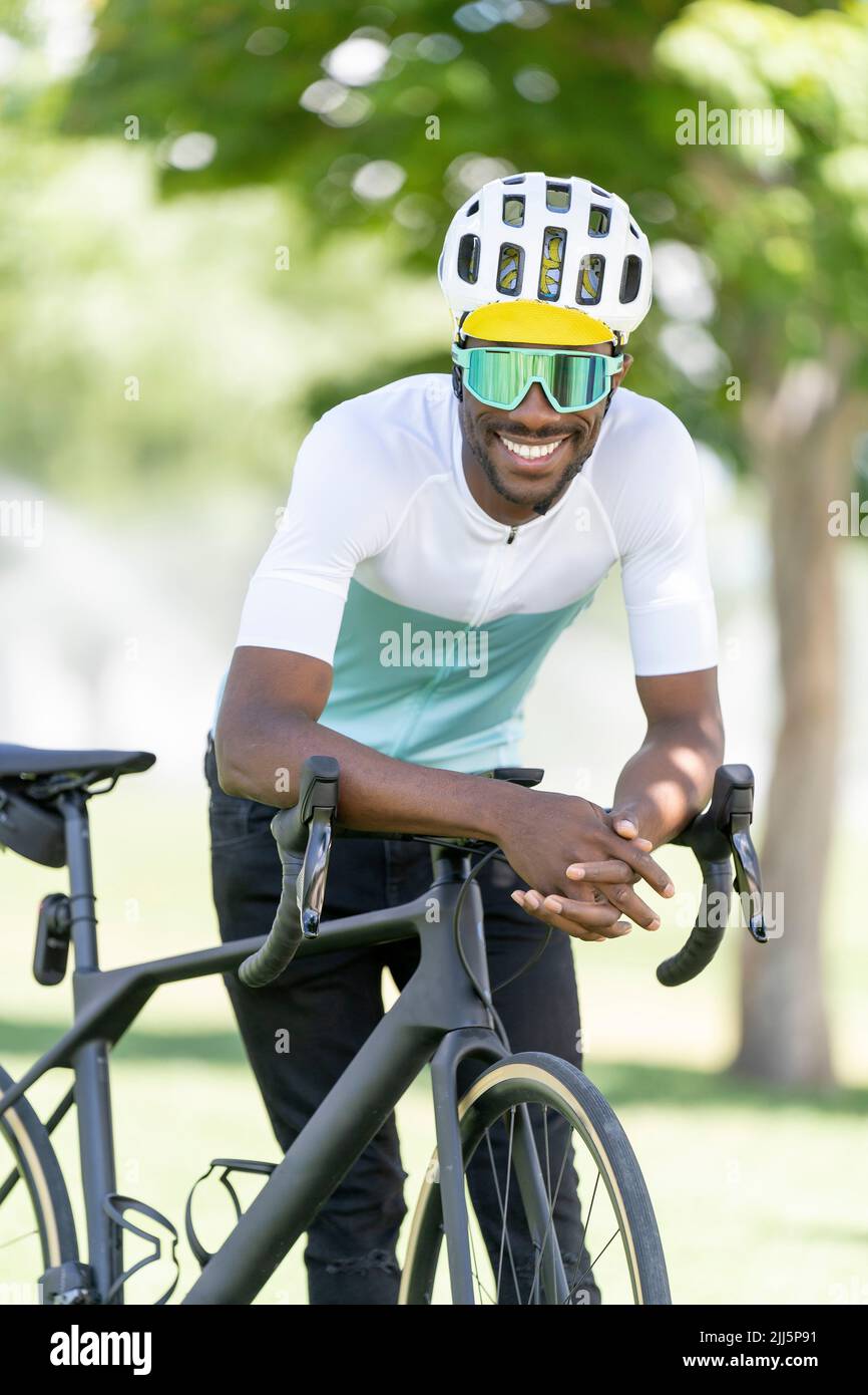 Un ciclista sorridente che si appoggia in bicicletta nel parco Foto Stock