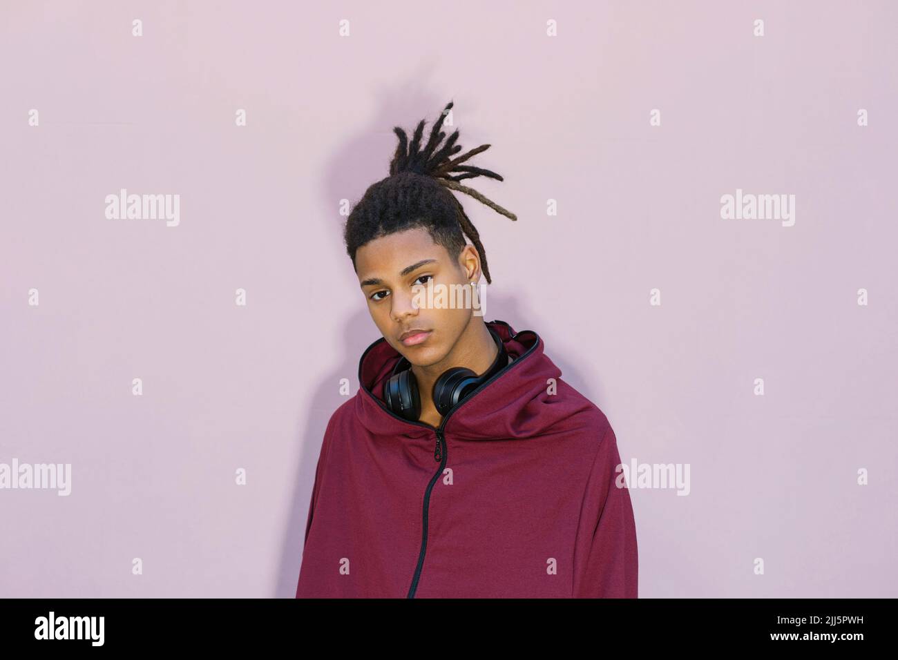 Giovane uomo con cuffie su sfondo rosa Foto Stock