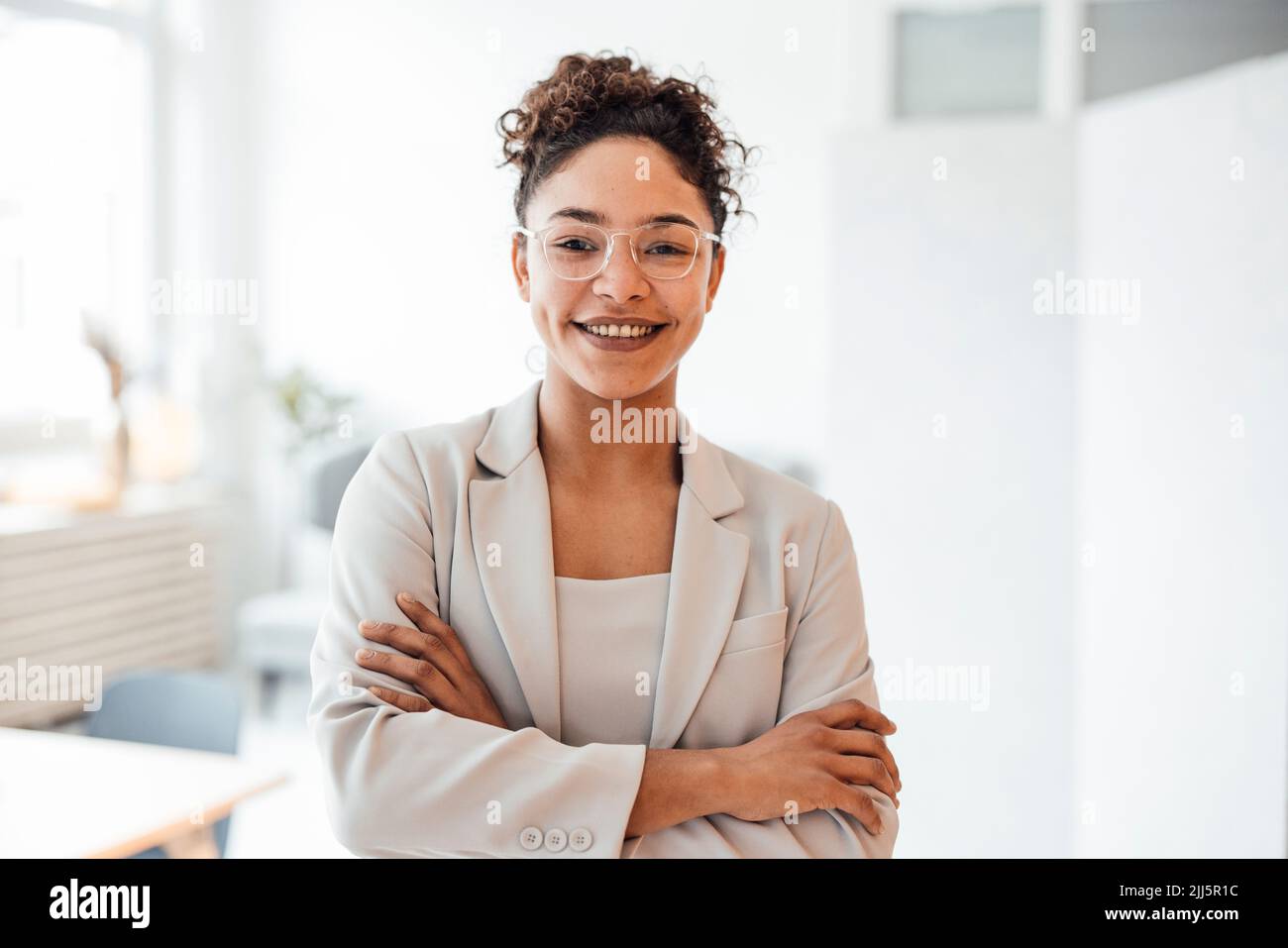 Donna d'affari felice che indossa occhiali in piedi in ufficio Foto Stock