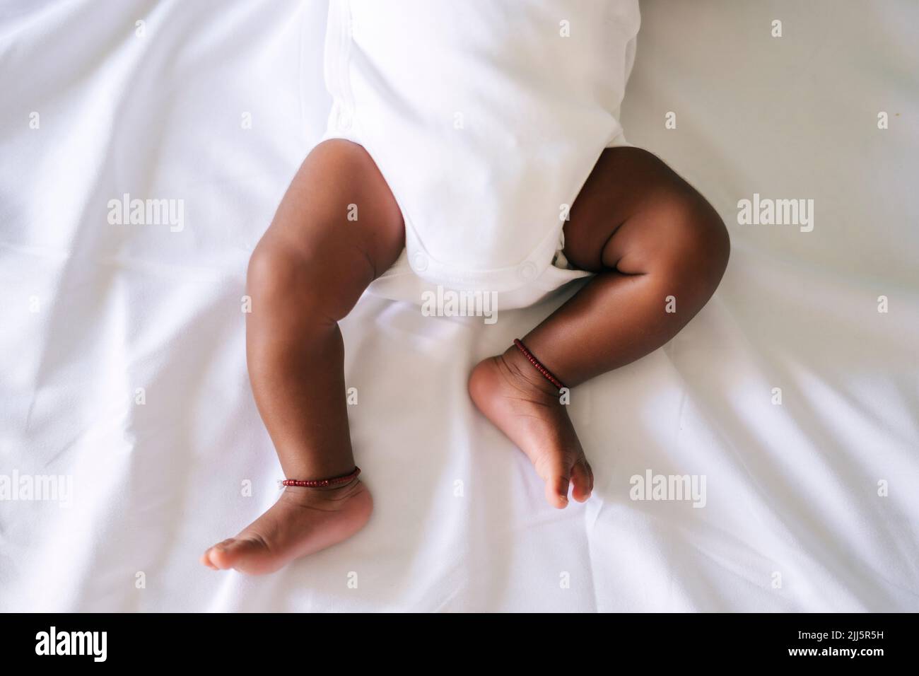 Bambino che indossa il bib sdraiato sul letto a casa Foto Stock