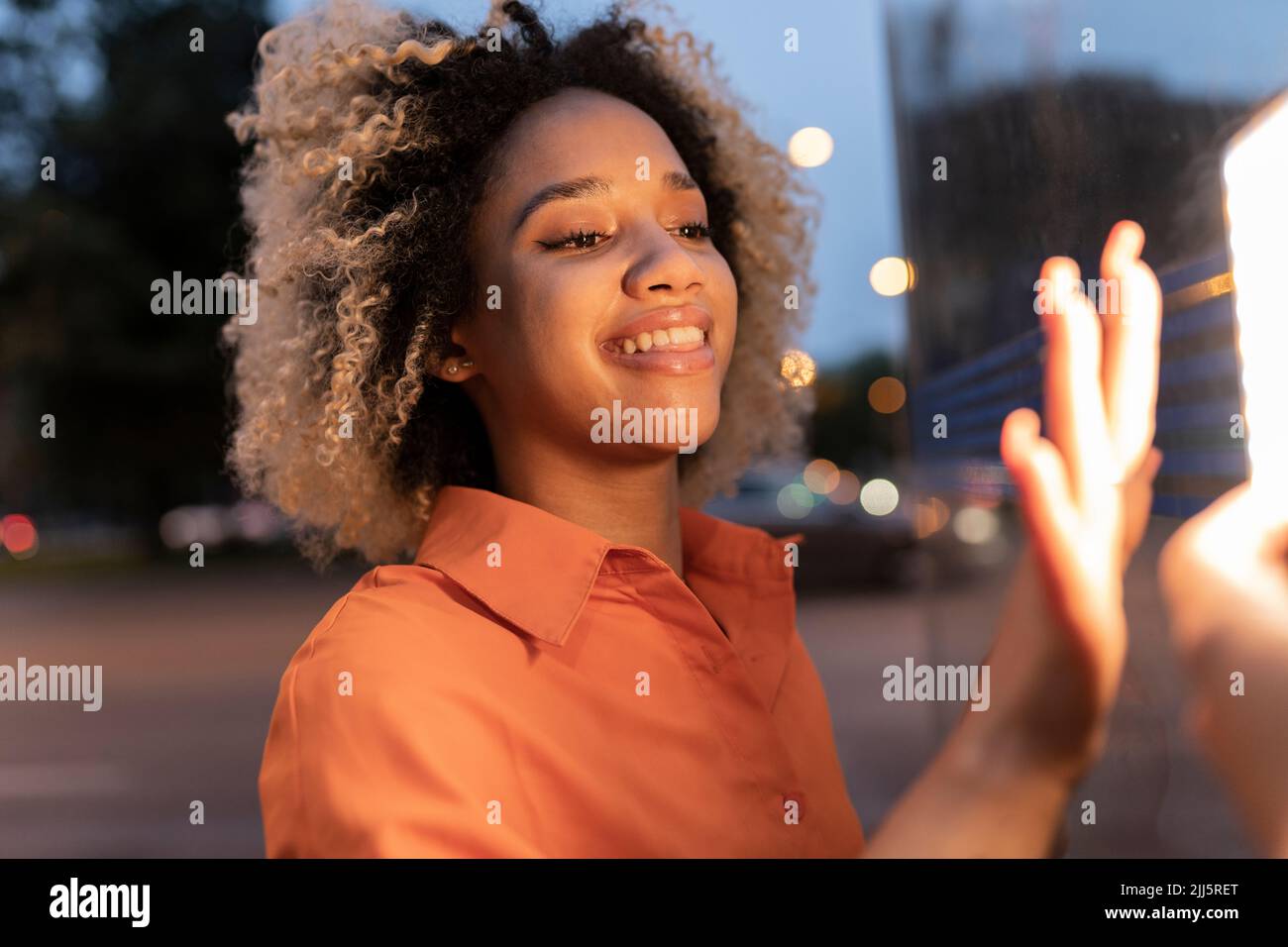 Donna curiosa che tocca l'attrezzatura di illuminazione illuminata di notte Foto Stock