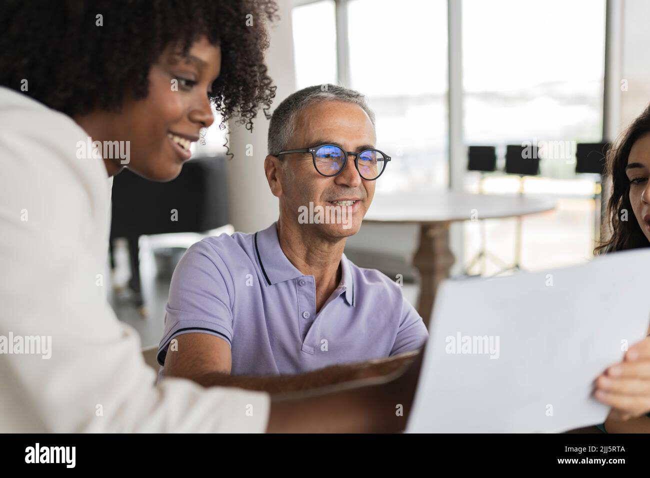 Uomo d'affari sorridente maturo che discute documento con le donne d'affari Foto Stock