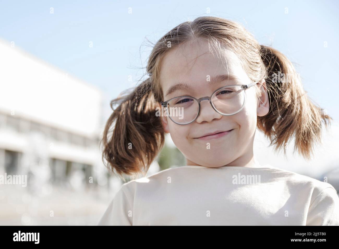 Ragazza sorridente con pigtail che indossa occhiali Foto Stock