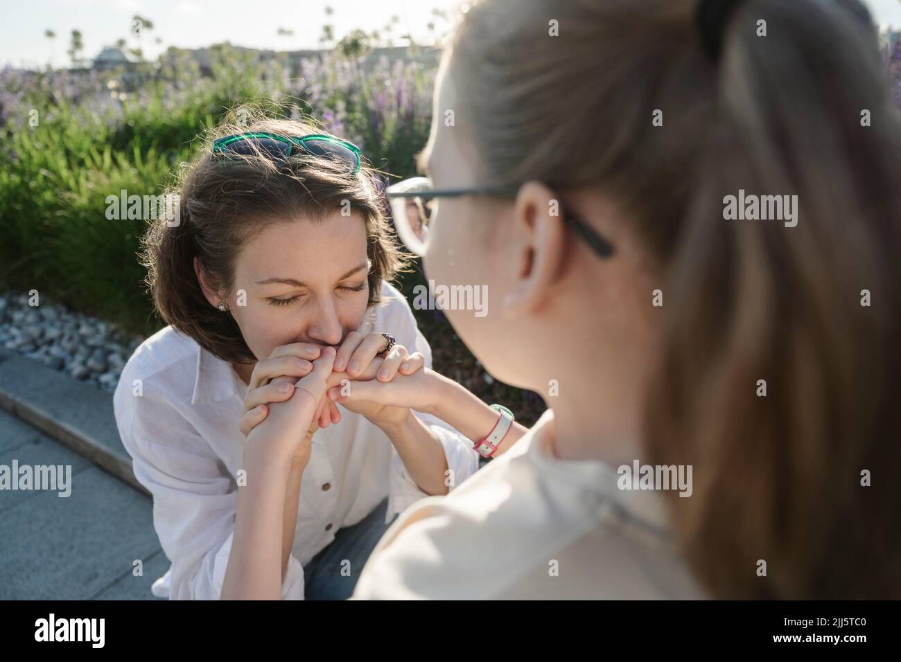 La madre bacia le mani della figlia al parco Foto Stock