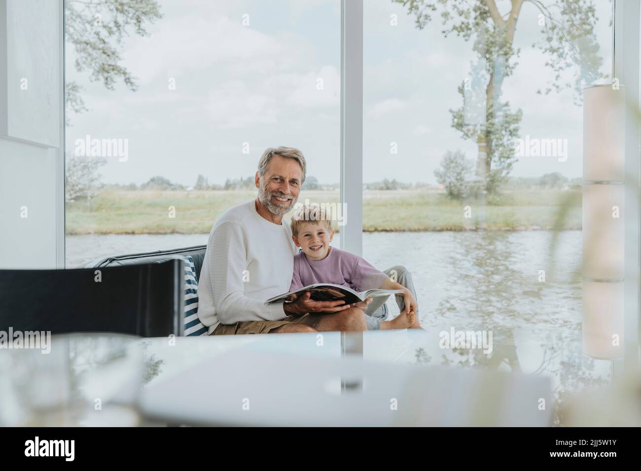 Uomo maturo felice con figlio seduto sul divano a casa Foto Stock