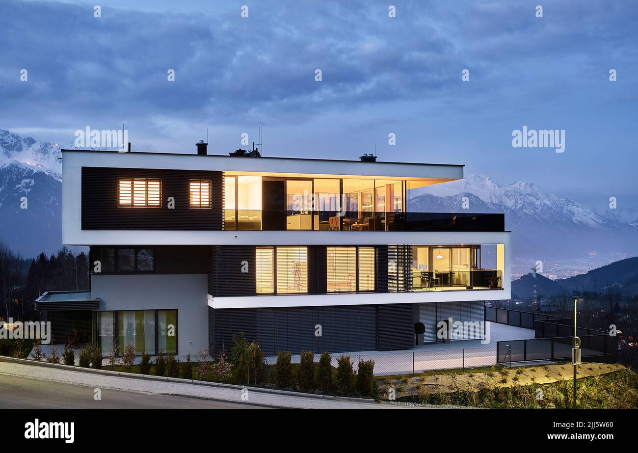 Austria, Tirolo, facciata illuminata di lussuosa casa a tre piani in montagna al crepuscolo Foto Stock