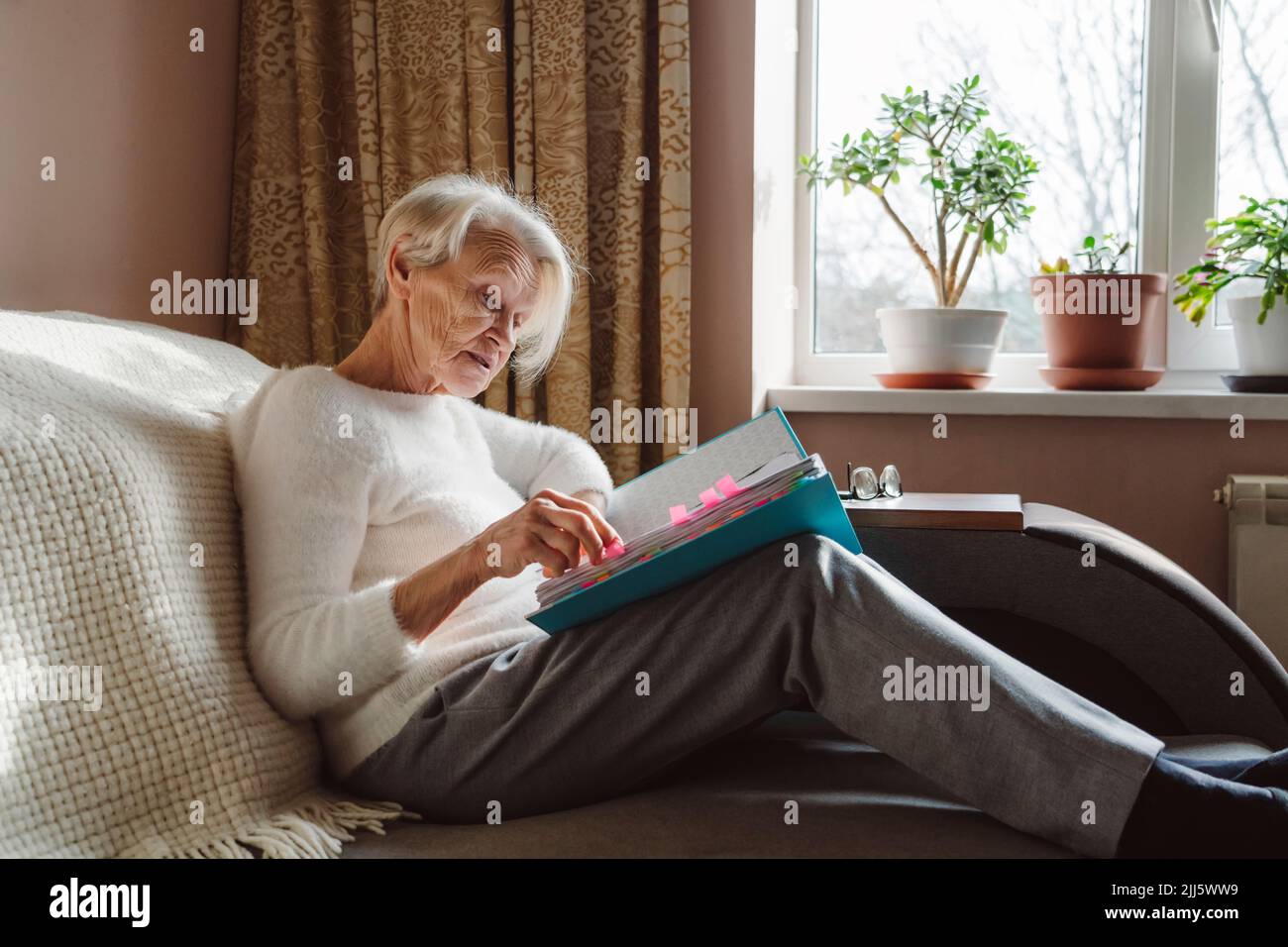 Donna anziana che legge documenti a casa Foto Stock