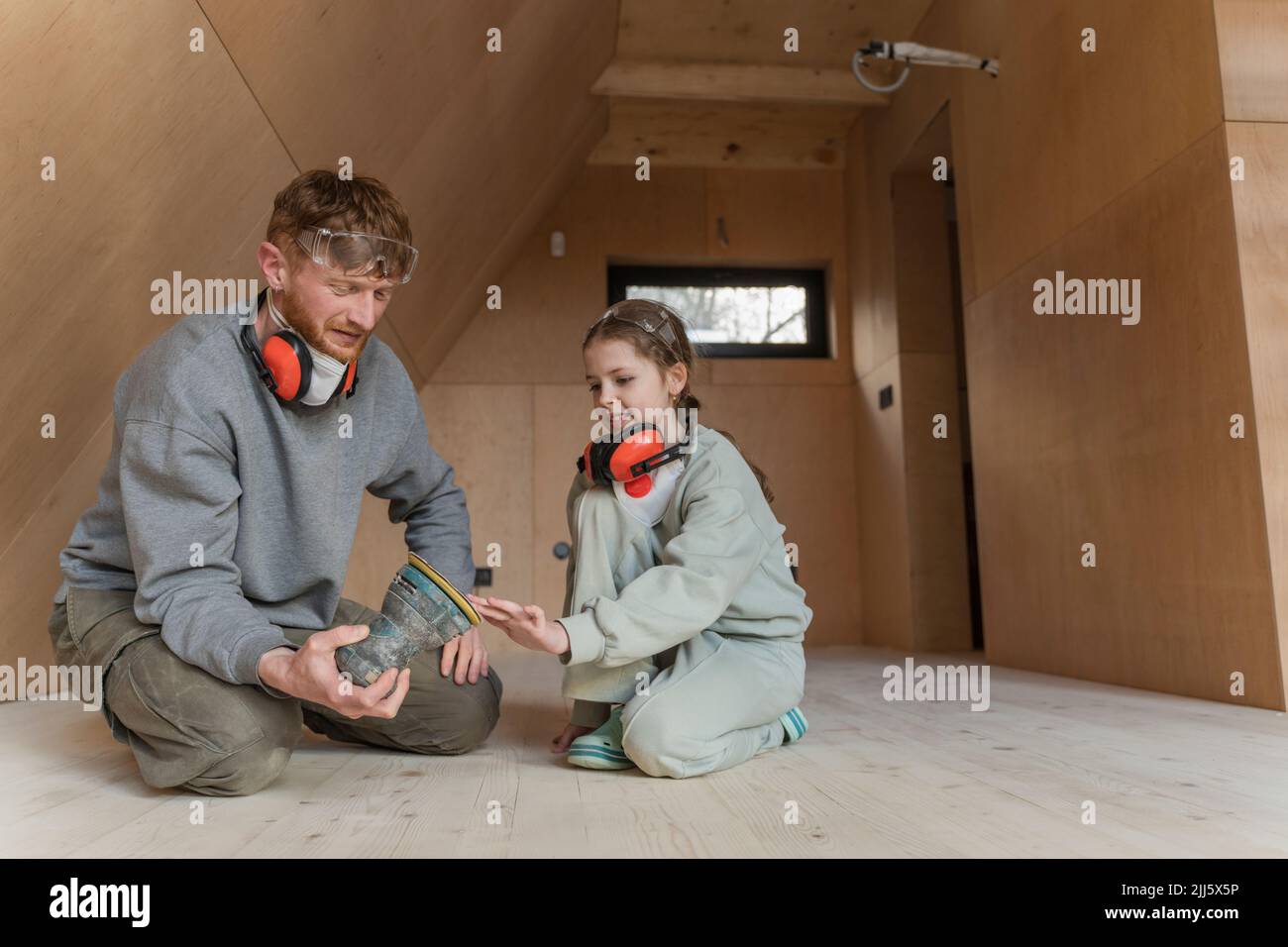 Padre e figlia levigano il pavimento nella loro nuova eco-house Foto Stock