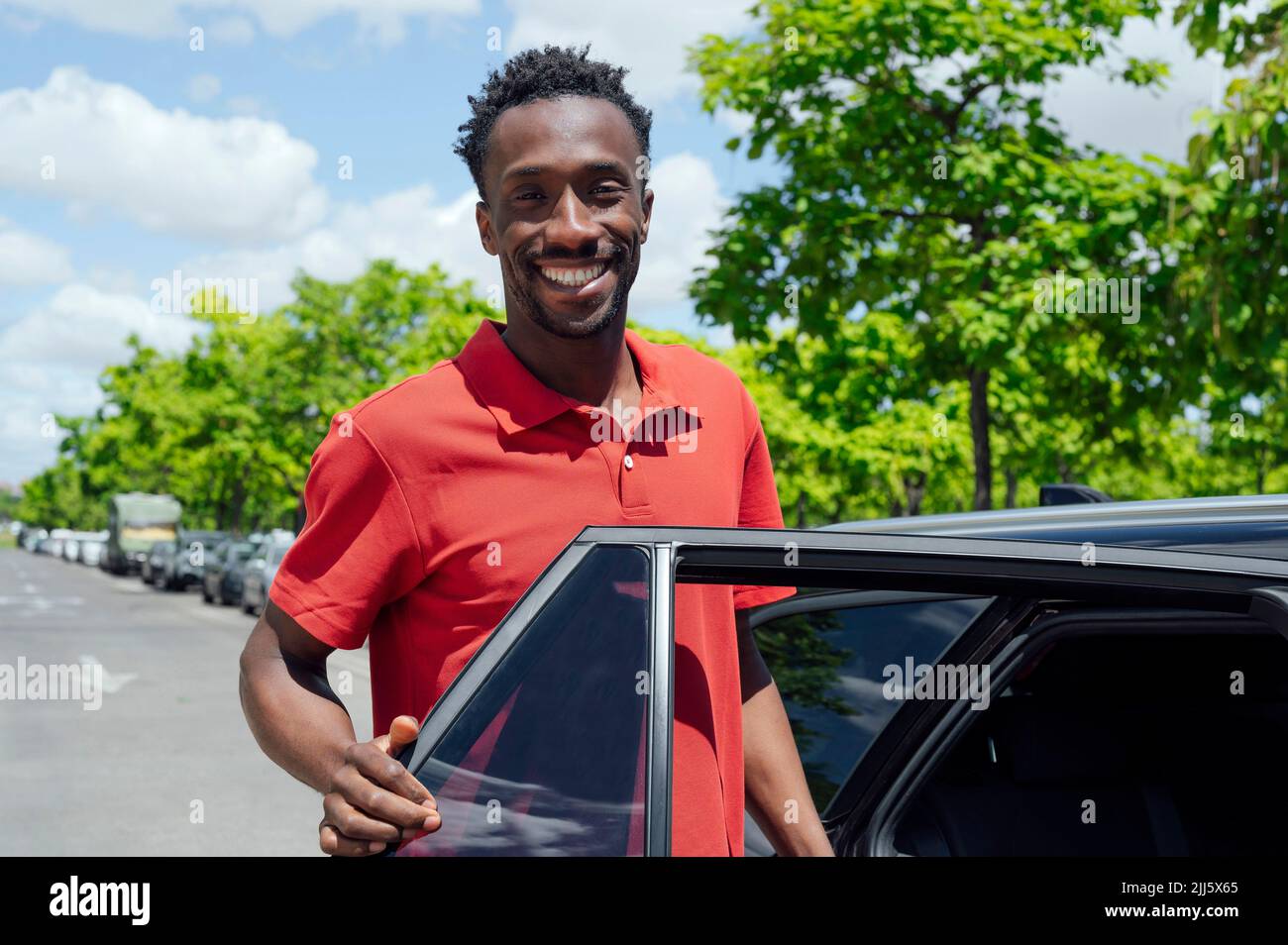 Uomo sorridente che entra in auto Foto Stock