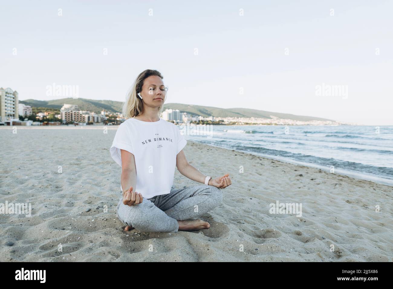 Donna sorridente con occhi chiusi meditando in spiaggia Foto Stock