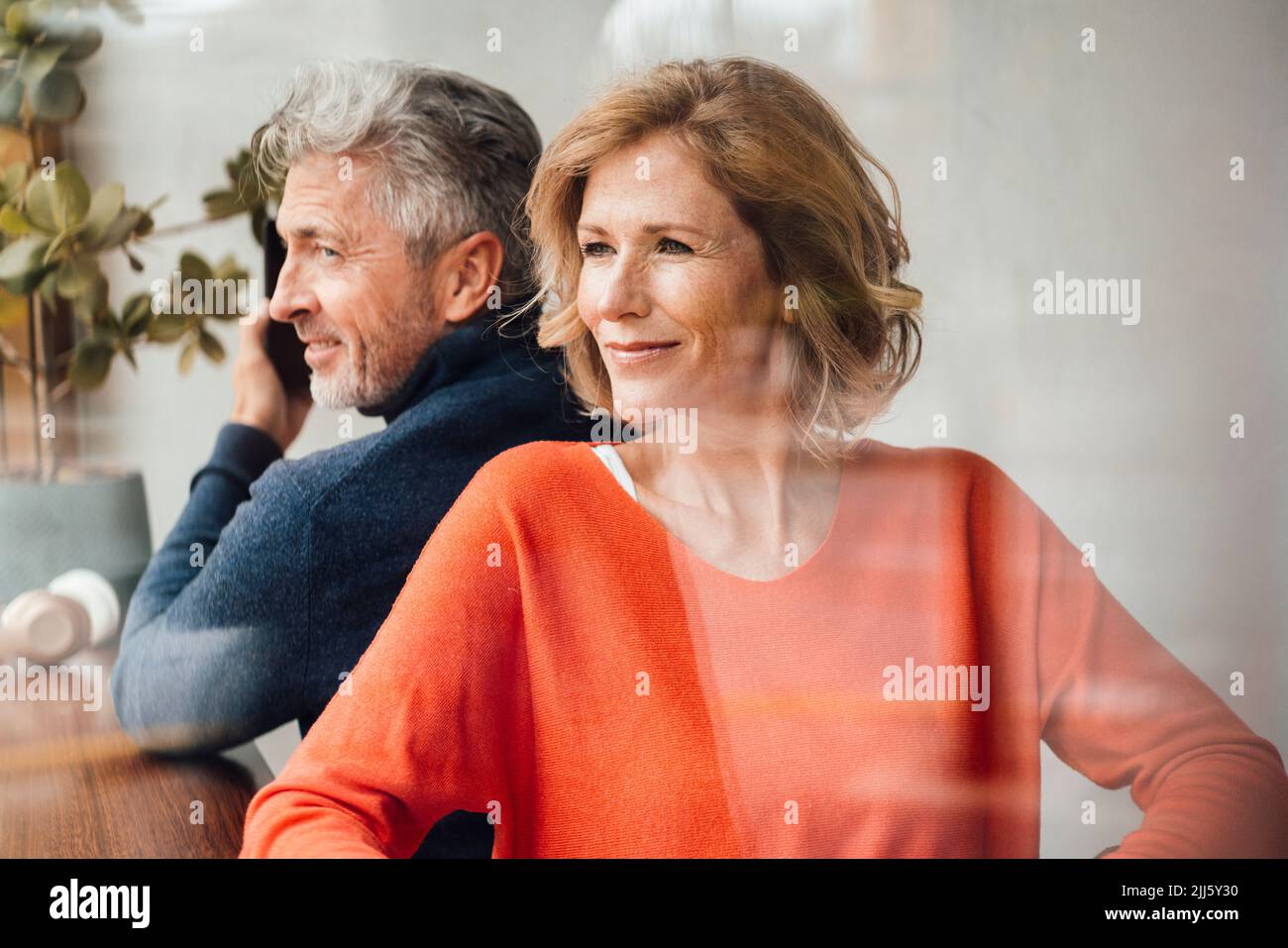 Coppia sorridente seduta insieme in un caffè visto attraverso il vetro Foto Stock