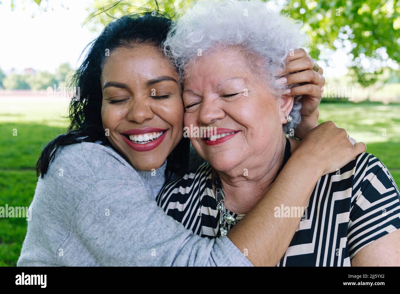 Donna felice che abbraccia la madre anziana nel parco Foto Stock