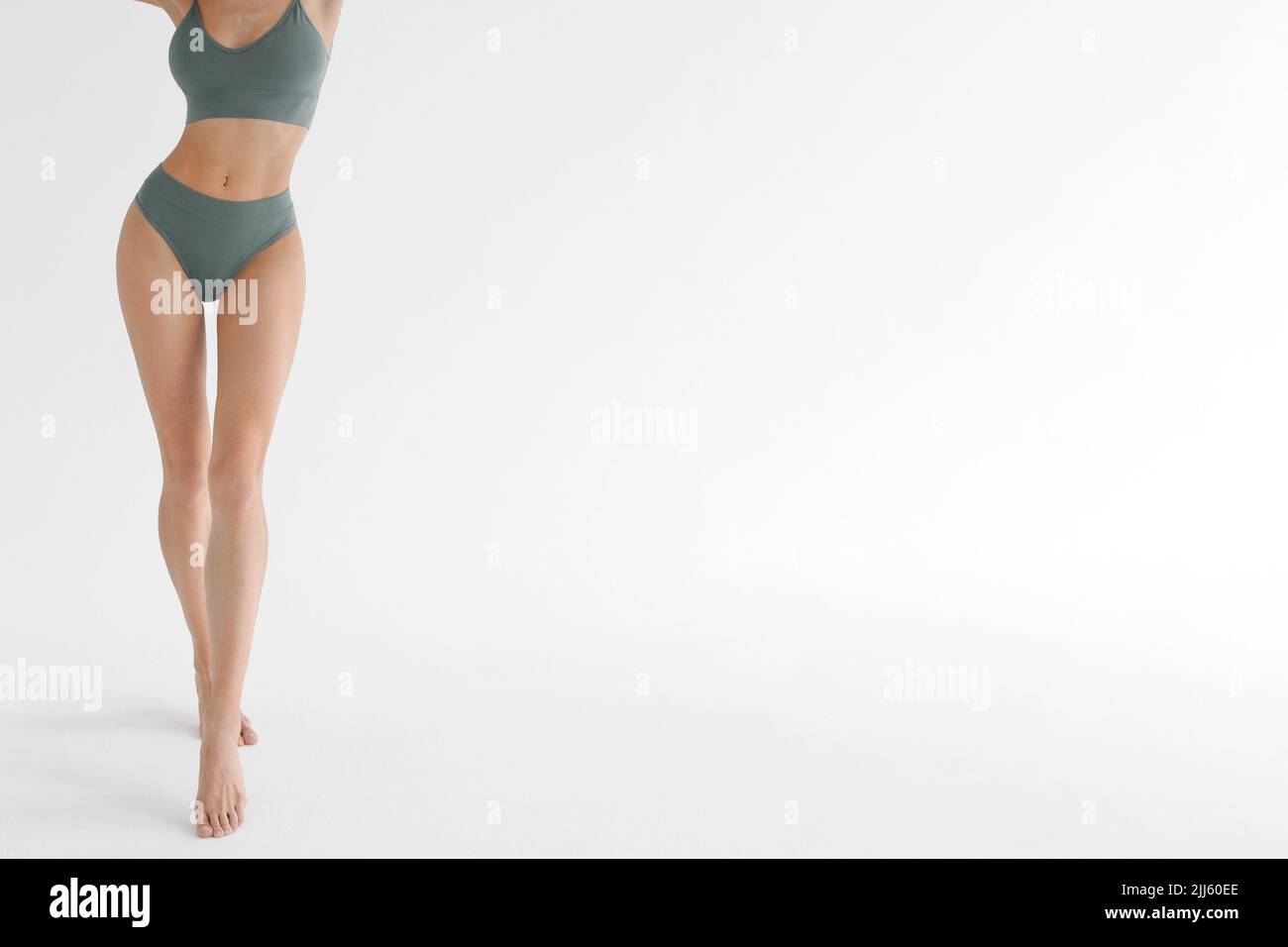 Gambe sottili abbronzate di una donna su sfondo bianco studio. Primo piano del modello di fitness in abbigliamento sportivo. Mutande o pubblicità di intimo. Cura della pelle Foto Stock