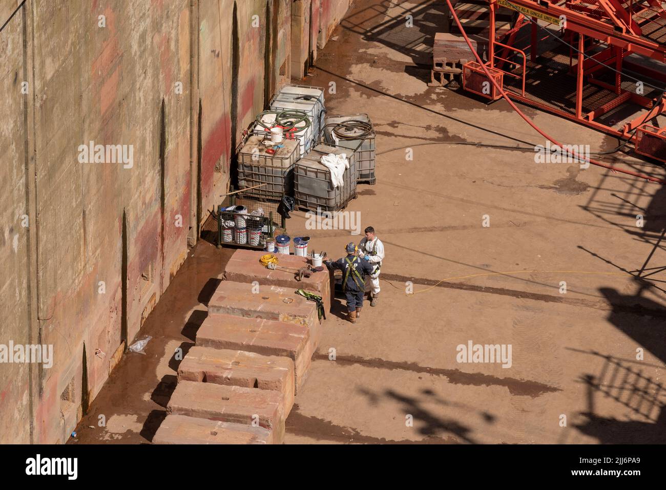 Falmouth, Cornovaglia, Inghilterra, Regno Unito. 2022. Una panoramica di un bacino asciutto, lavoratori che si rompono dalla pittura dello scafo di una nave blu. Foto Stock