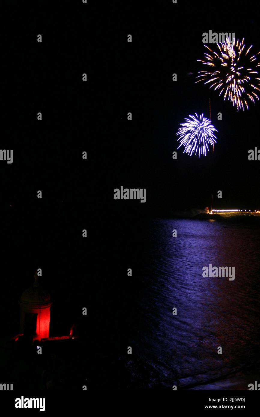 Una bella vista dei fuochi d'artificio riflessi nel mare in una notte di nero scuro Foto Stock