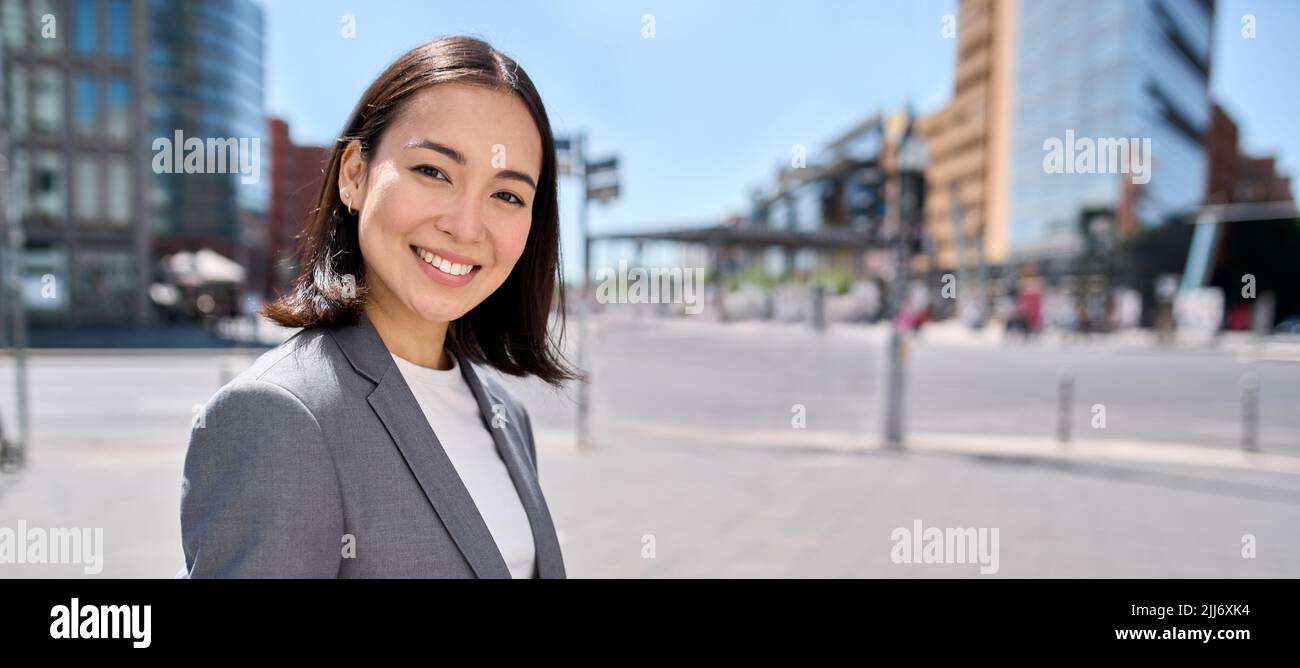 Giovane fiduciosa sorridente donna asiatica d'affari in piedi sulla strada della città, banner. Foto Stock