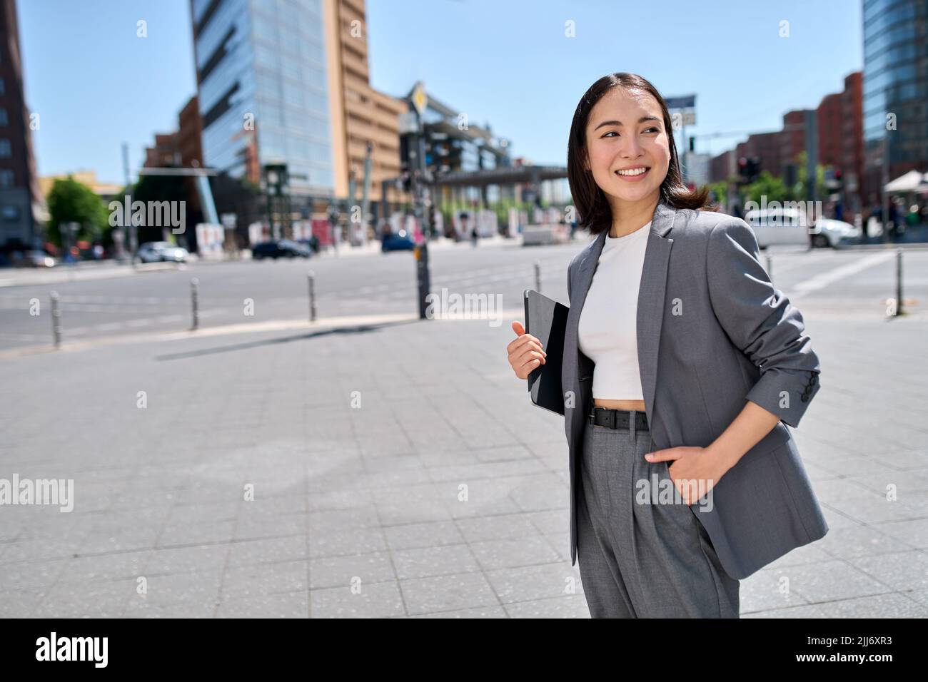 Sorridendo fiducioso imprenditore asiatico giovane donna in piedi sulla strada della città. Foto Stock