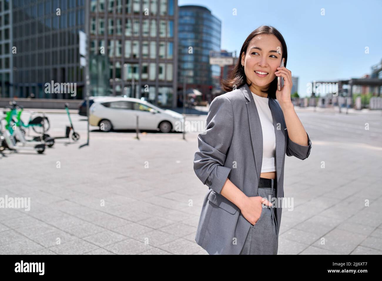 Giovane donna felice asiatico d'affari indossa vestito parlare al telefono sulla strada della città. Foto Stock