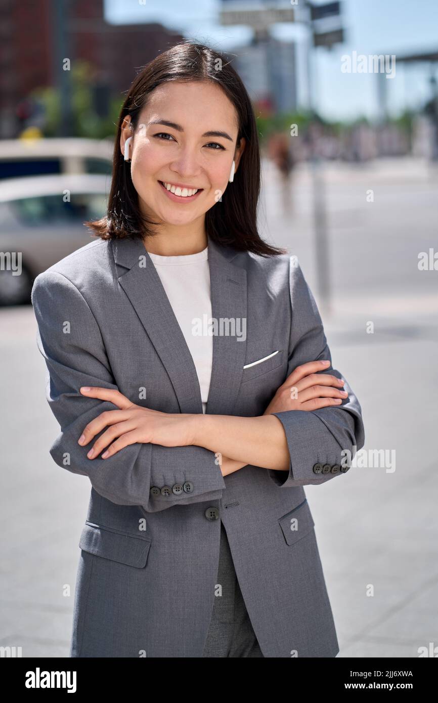 Giovane donna d'affari asiatica sorridente e sicura in piedi sulla strada della città. Foto Stock