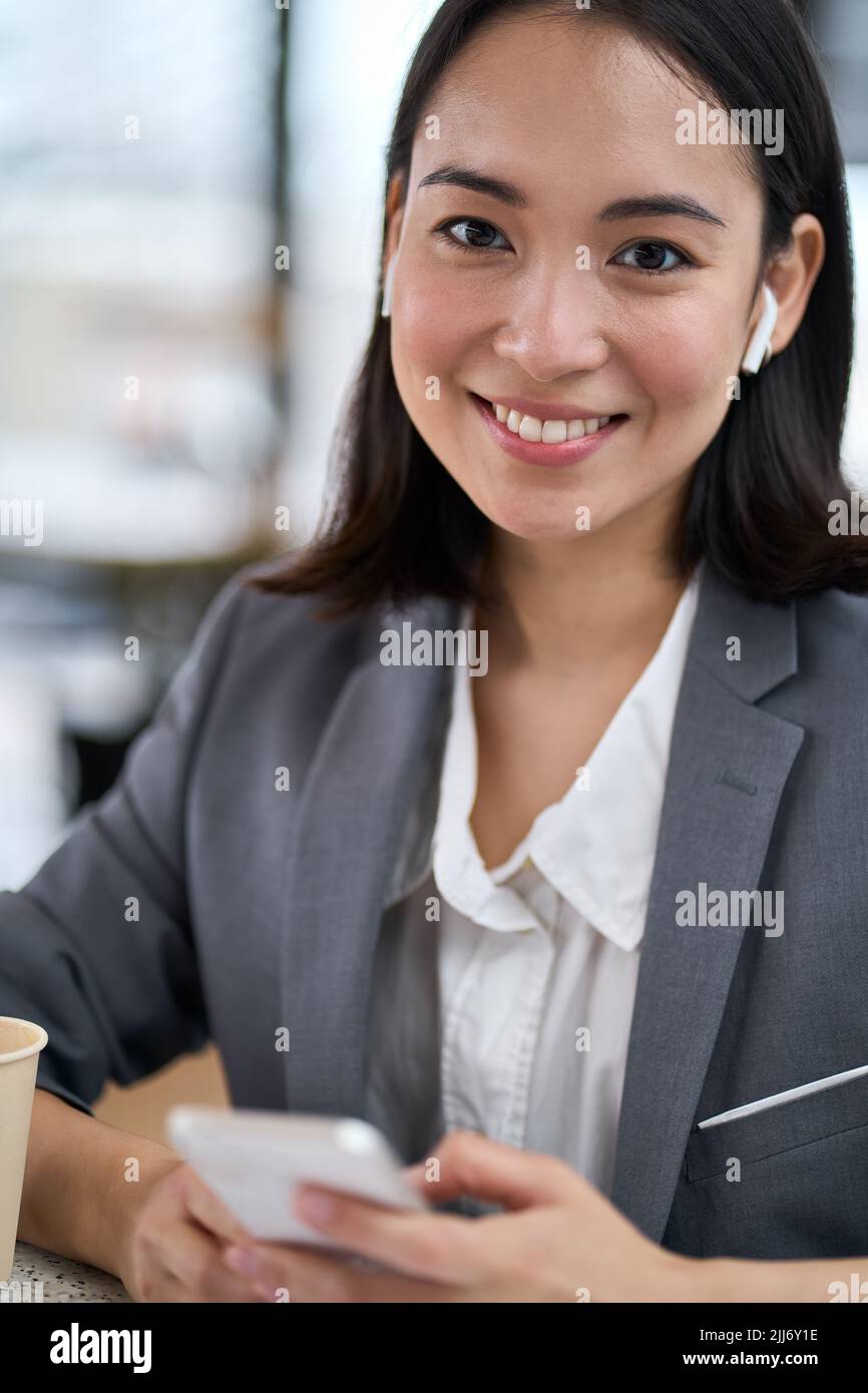 Giovane donna asiatica sorridente che indossa il vestito usando il telefono. Verticale Foto Stock