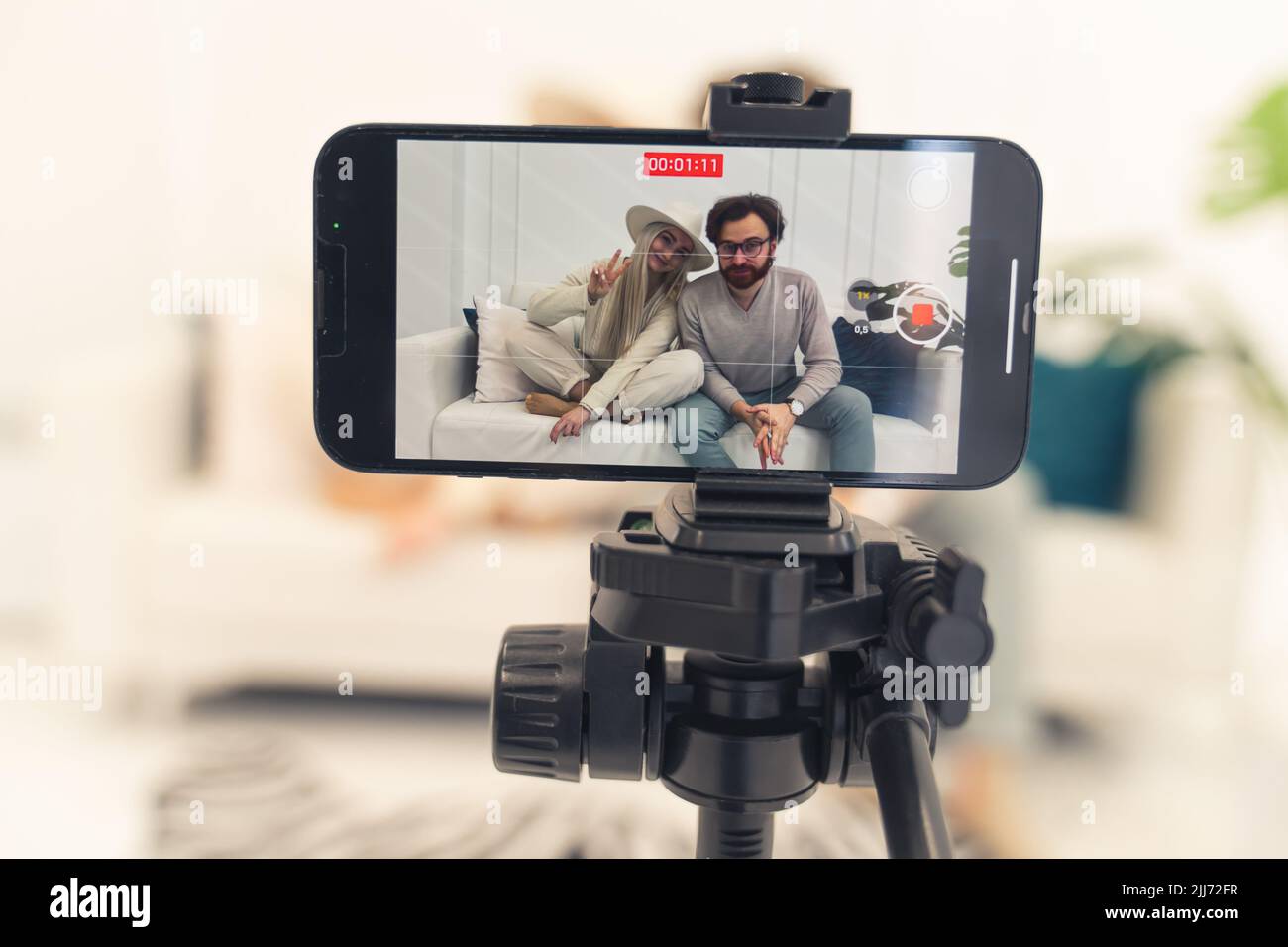 Registrazione video di due persone bianche care seduto sul divano fatto con l'uso di smartphone - primo piano studio sparare. Foto di alta qualità Foto Stock