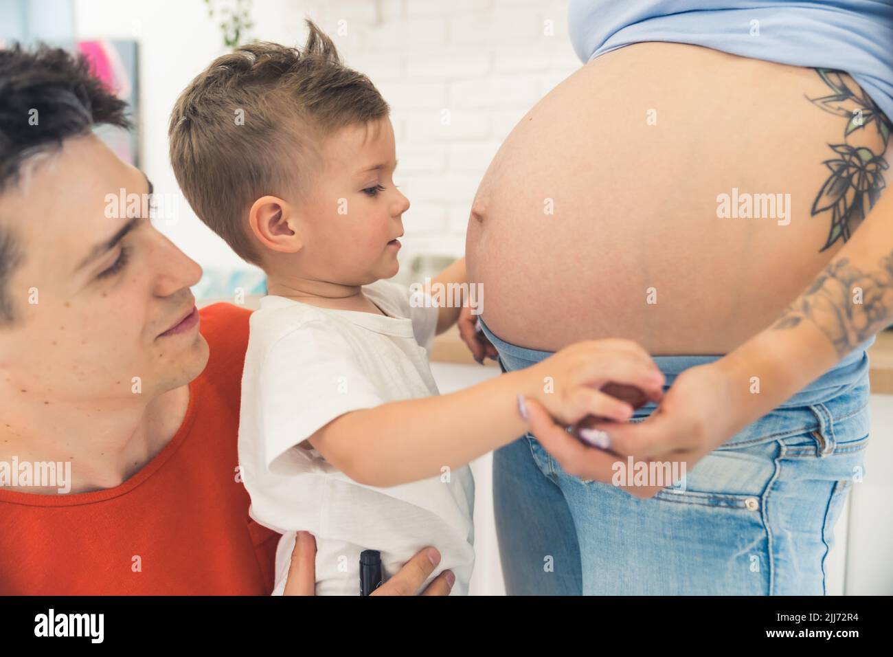 Famiglia di tre in attesa di un nuovo bambino. Adorabile ragazzo preschooler che guarda il ventre incinta della madre con stupore. Foto di alta qualità Foto Stock