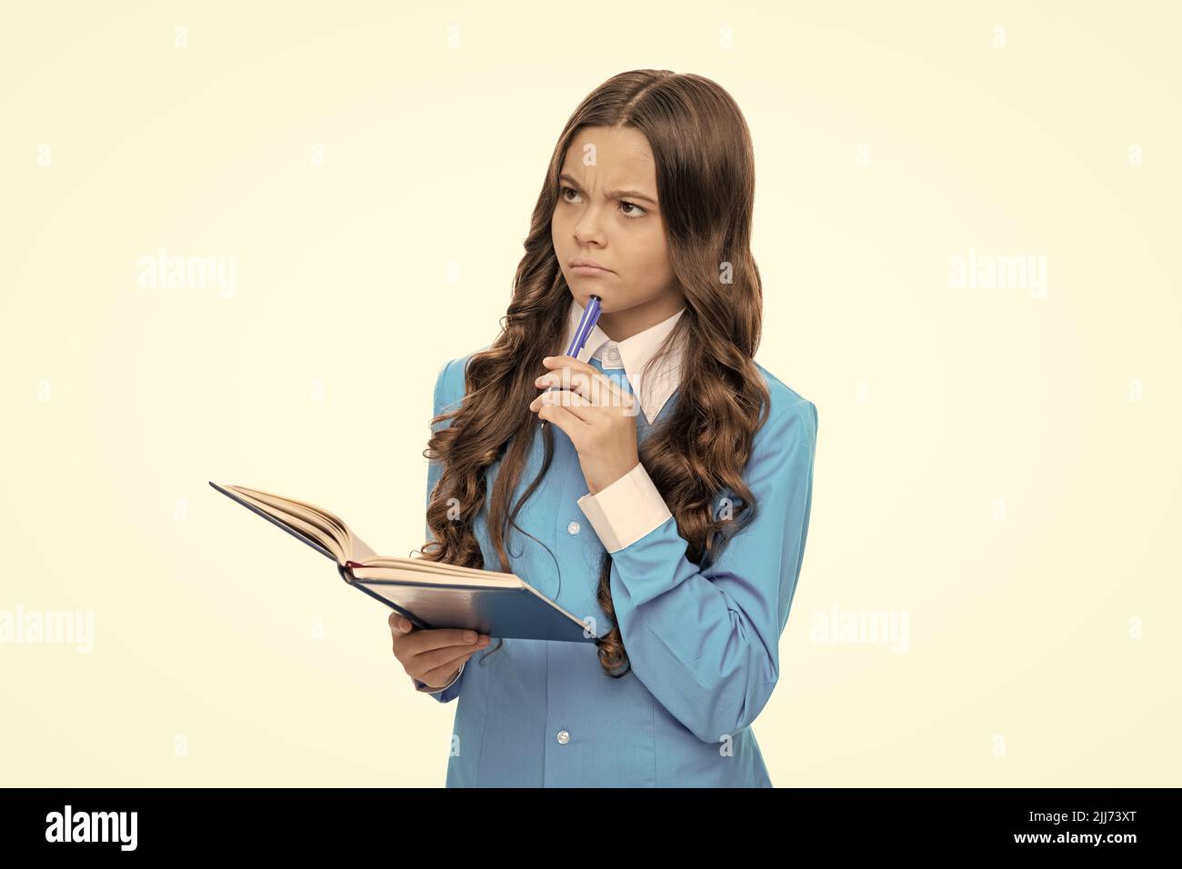 Bambino fantasioso con lo sguardo premuroso genera l'idea che tiene la penna e il libro della scuola, immaginazione Foto Stock