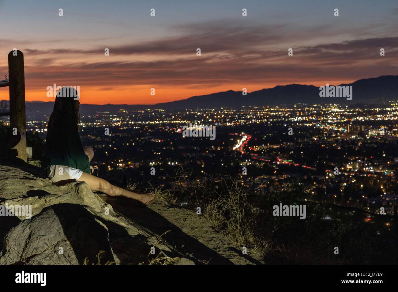 Lone femmina guarda il tramonto che domina la Valle di Los Angeles Foto Stock