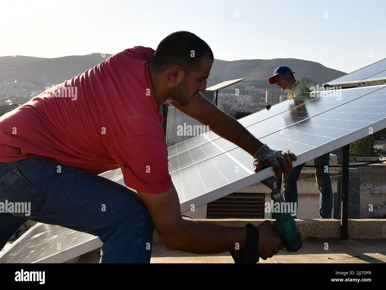 Damasco, Siria. 23rd luglio 2022. I lavoratori installano pannelli solari in cima a un edificio a Damasco, Siria, 23 luglio 2022. I sistemi di energia solare stanno diventando più popolari a Damasco come conseguenza dei lunghi tagli di energia. Credit: Ammar Safarjalani/Xinhua/Alamy Live News Foto Stock