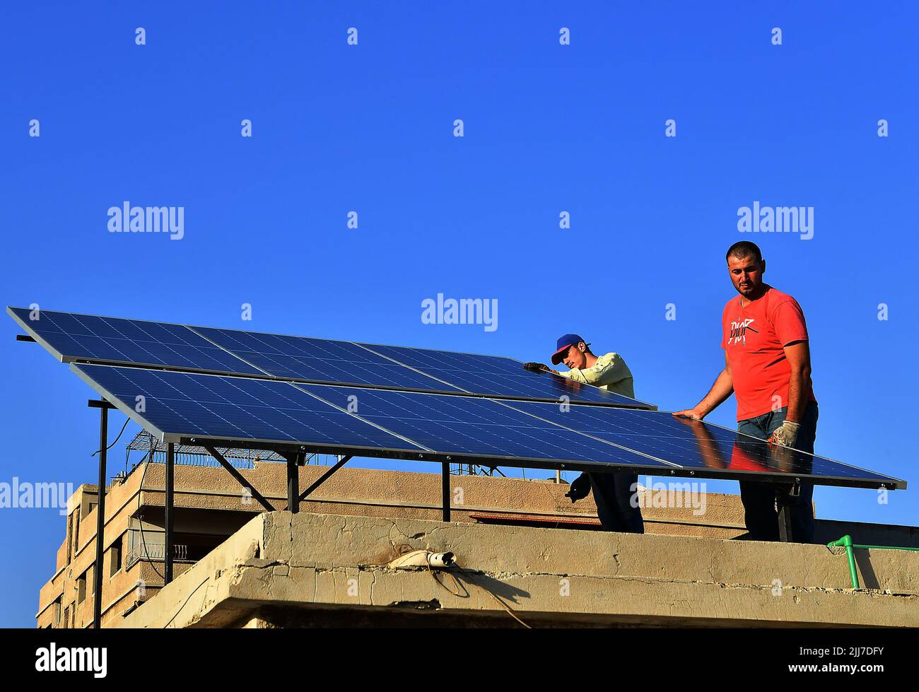 Damasco, Siria. 23rd luglio 2022. I lavoratori installano pannelli solari in cima a un edificio a Damasco, Siria, 23 luglio 2022. I sistemi di energia solare stanno diventando più popolari a Damasco come conseguenza dei lunghi tagli di energia. Credit: Ammar Safarjalani/Xinhua/Alamy Live News Foto Stock