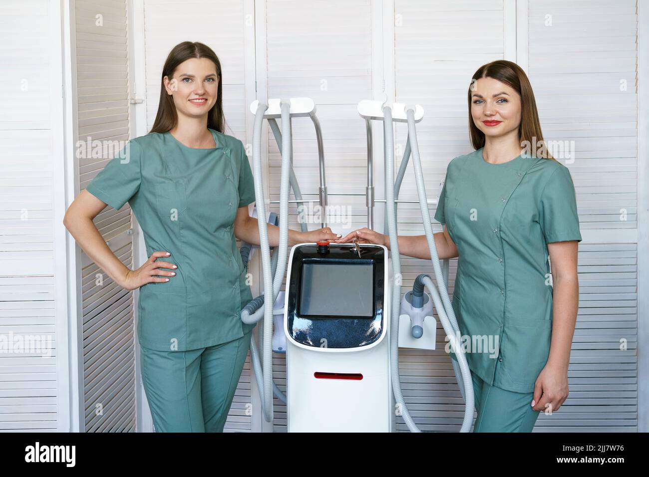 Due donne specialisti in cosmetologia hardware stand in sala massaggi presso l'apparecchiatura di terapia laser. Concetto di cura della pelle e del corpo. Foto Stock