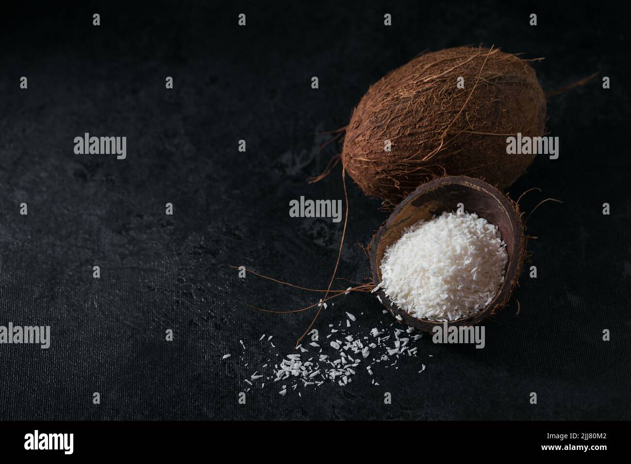 Cocco intero con scaglie di cocco su sfondo nero Foto Stock