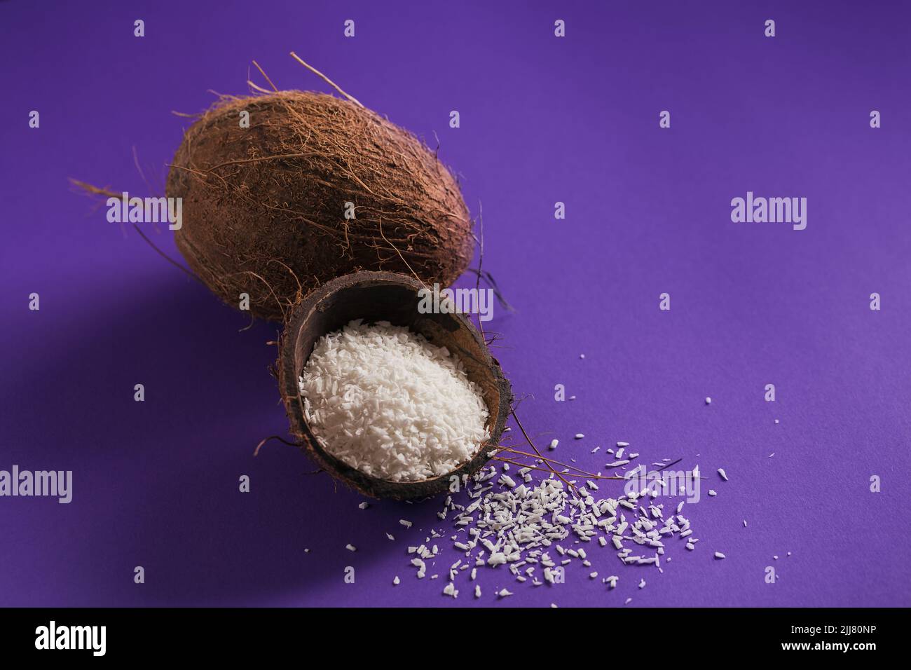 Cocco intero con fiocchi di cocco su uno sfondo perple Foto Stock