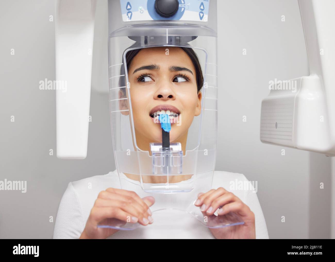 Perché questa cosa fa quel rumore, una giovane donna che guarda ansiosa mentre usa una macchina a raggi X in un ufficio dentistico. Foto Stock