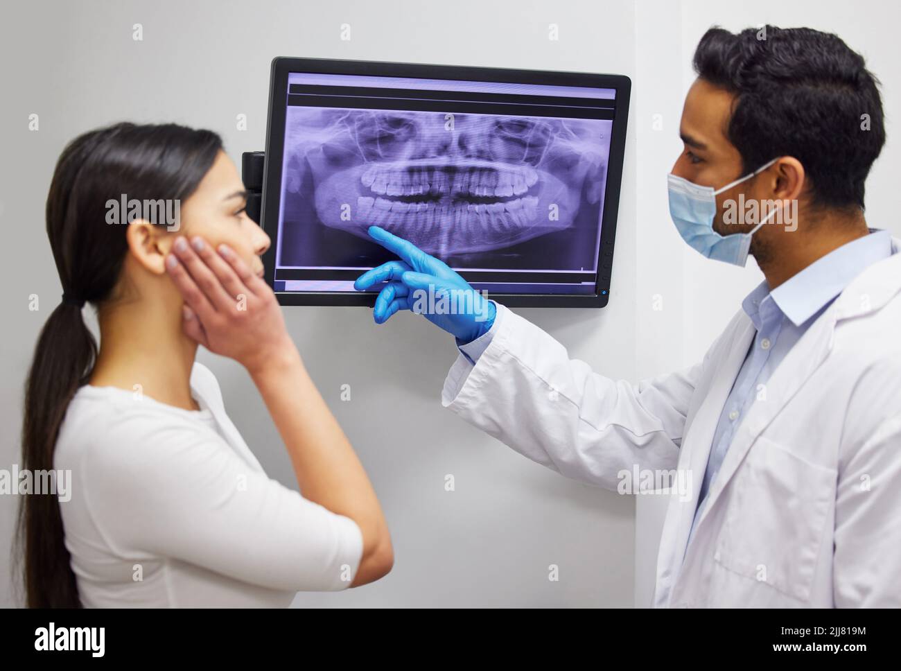 Ecco perché si avverte dolore in quella zona. Un dentista che discute i risultati di un paziente denti x ray. Foto Stock