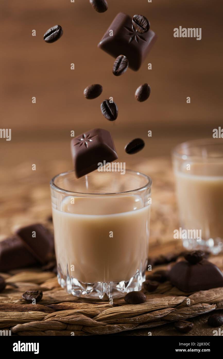 Bicchieri corti di liquore alla crema irlandese o caffè Liquore con cioccolato volante e chicchi di caffè Foto Stock