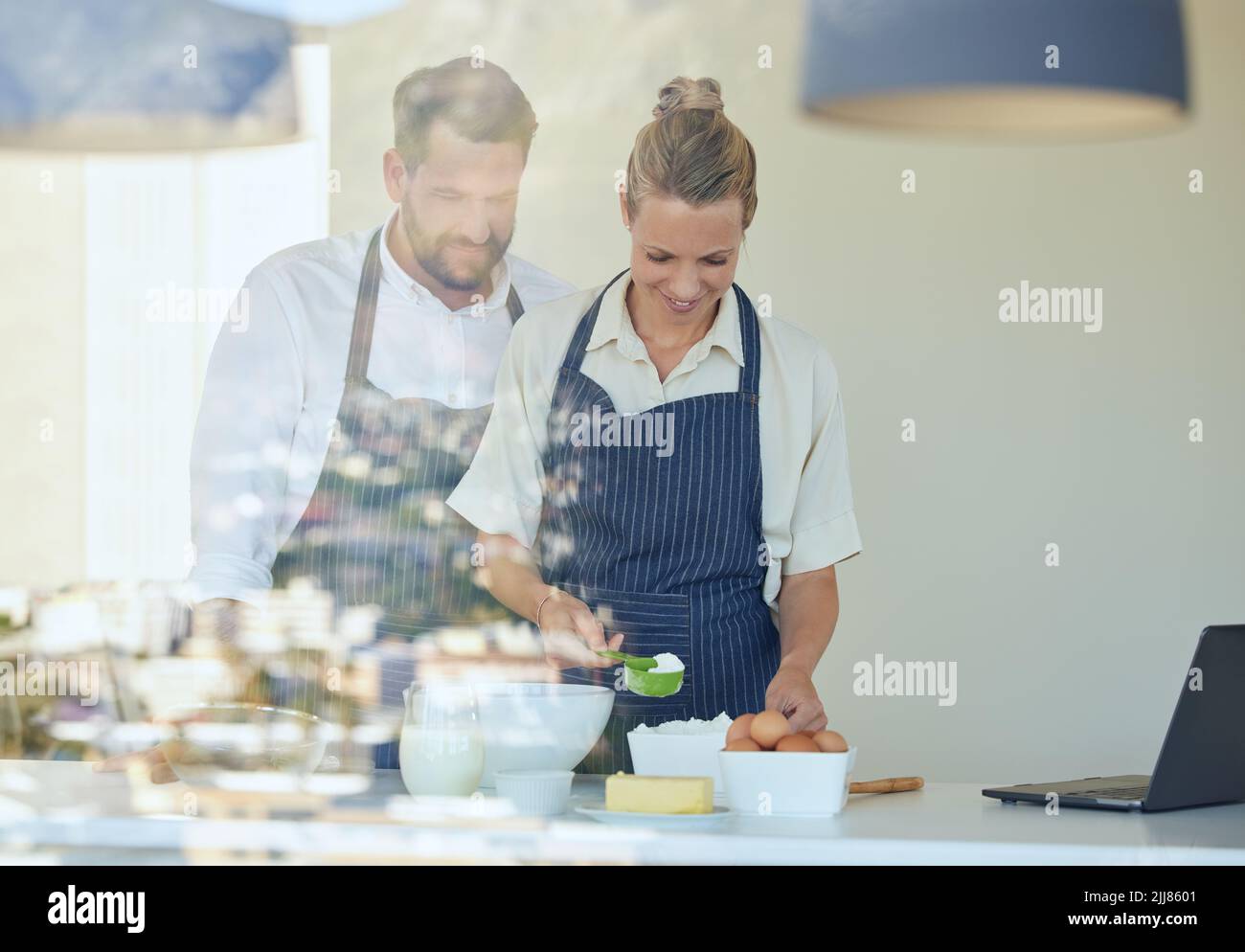 Un cucchiaio di questo. Una giovane coppia che cucinano insieme a casa. Foto Stock