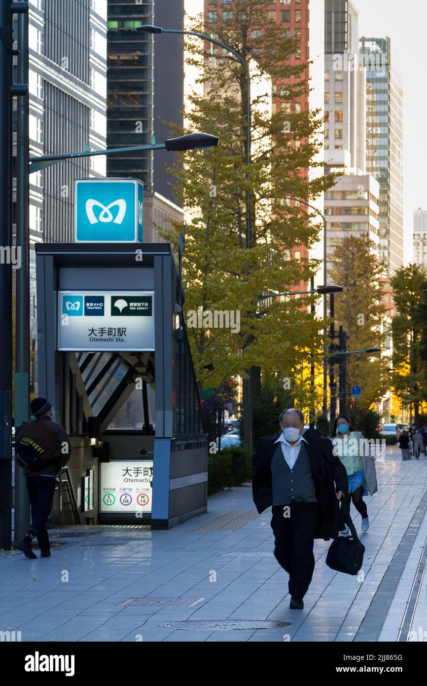 Un salarista giapponese, che indossa una maschera chirurgica contro COVID19 infezioni, cammina per strada a Otemachi, Tokyo, Giappone. Foto Stock