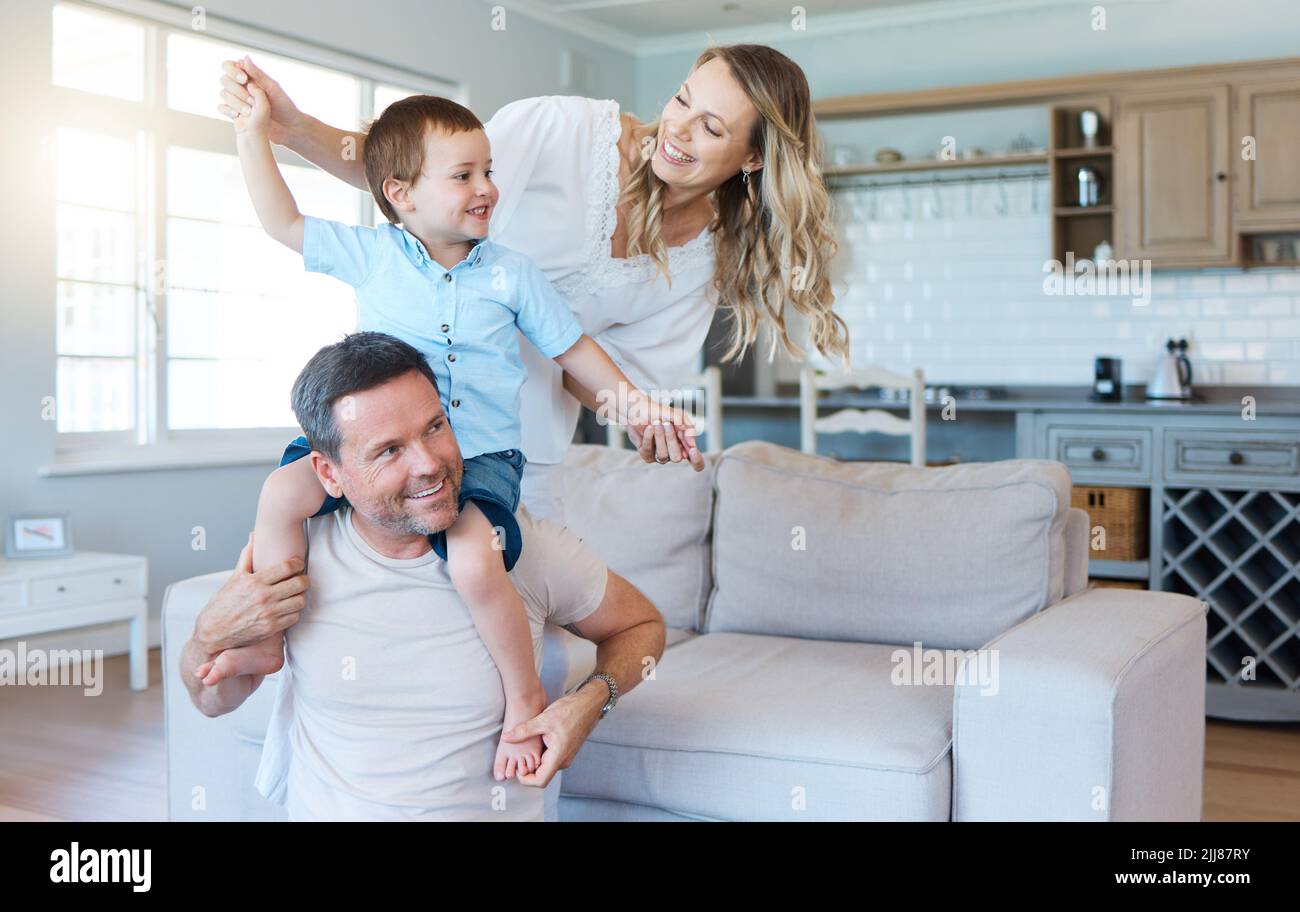Essere una famiglia significa essere una parte di qualcosa: Due genitori che giocano con il loro figlio a casa. Foto Stock