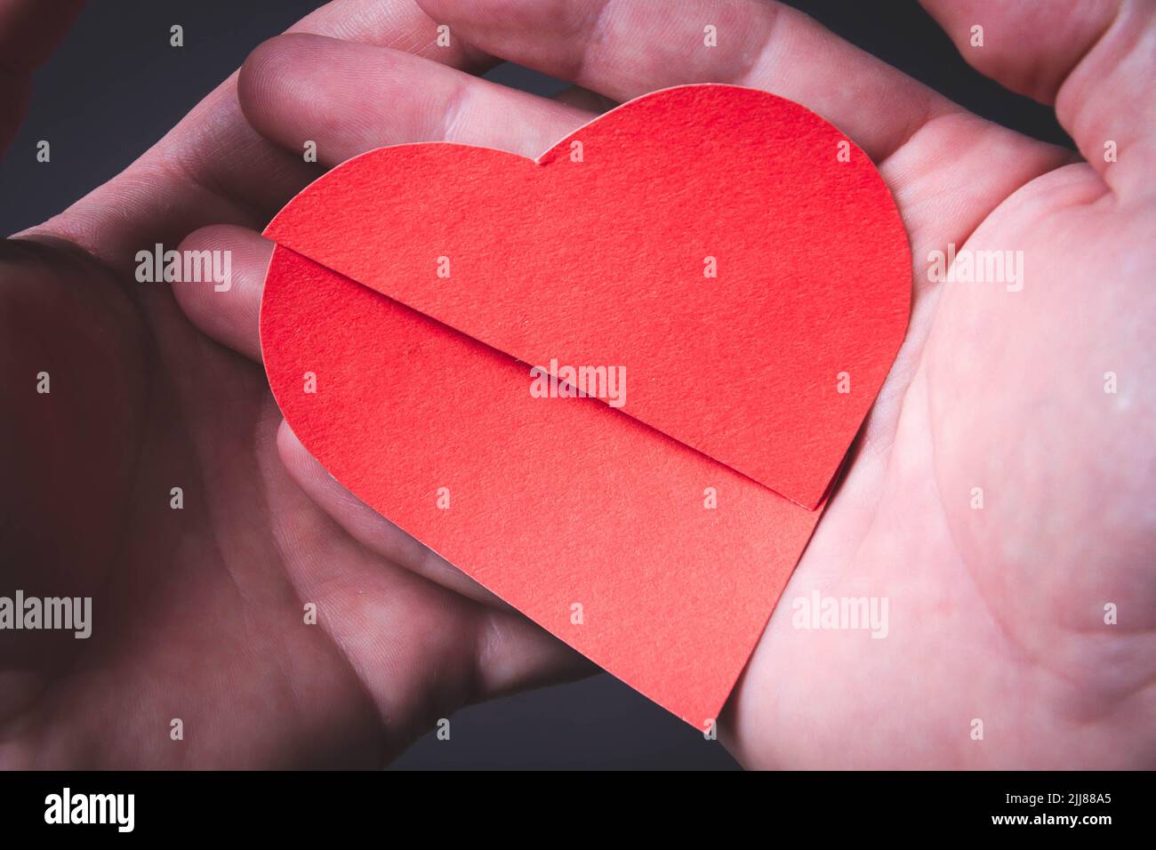 Cuore rotto. Divorzio di una coppia sposata. Matrimonio rotto. Cuore in mano e forbici. Foto Stock