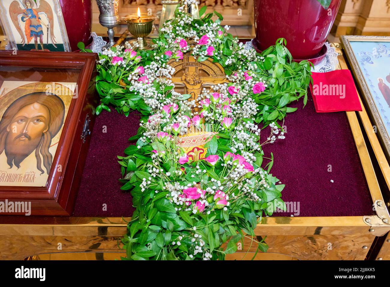 Una grande croce con Gesù Cristo è decorata con pervinca sull'altare della chiesa. Foto Stock